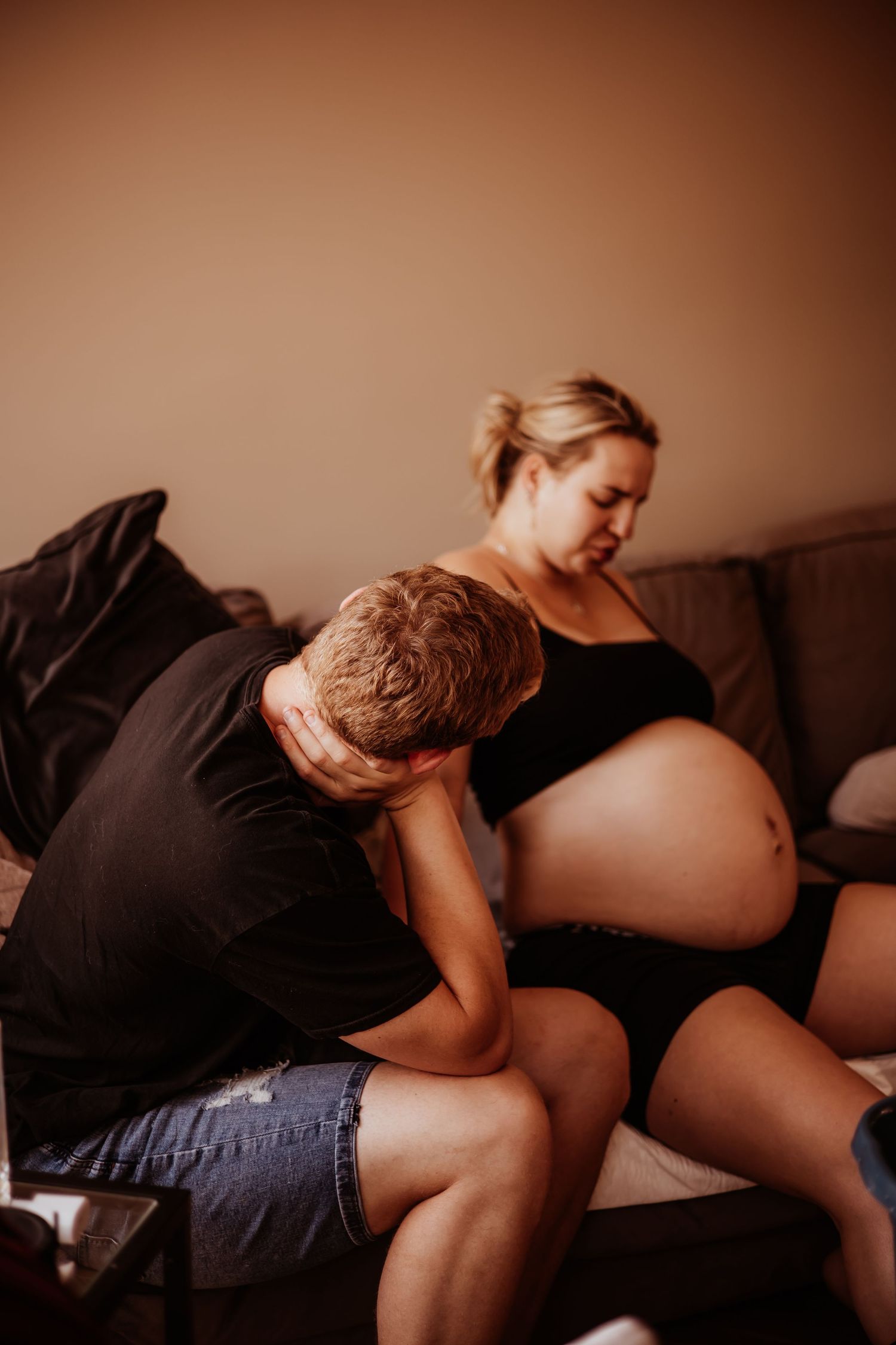 Partner resting head on pregnant woman's belly during labor at home.