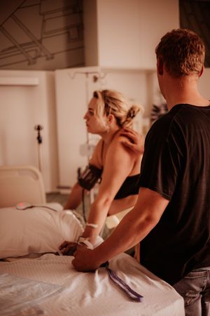 Partner comforting and supporting woman during active labor in hospital delivery room.