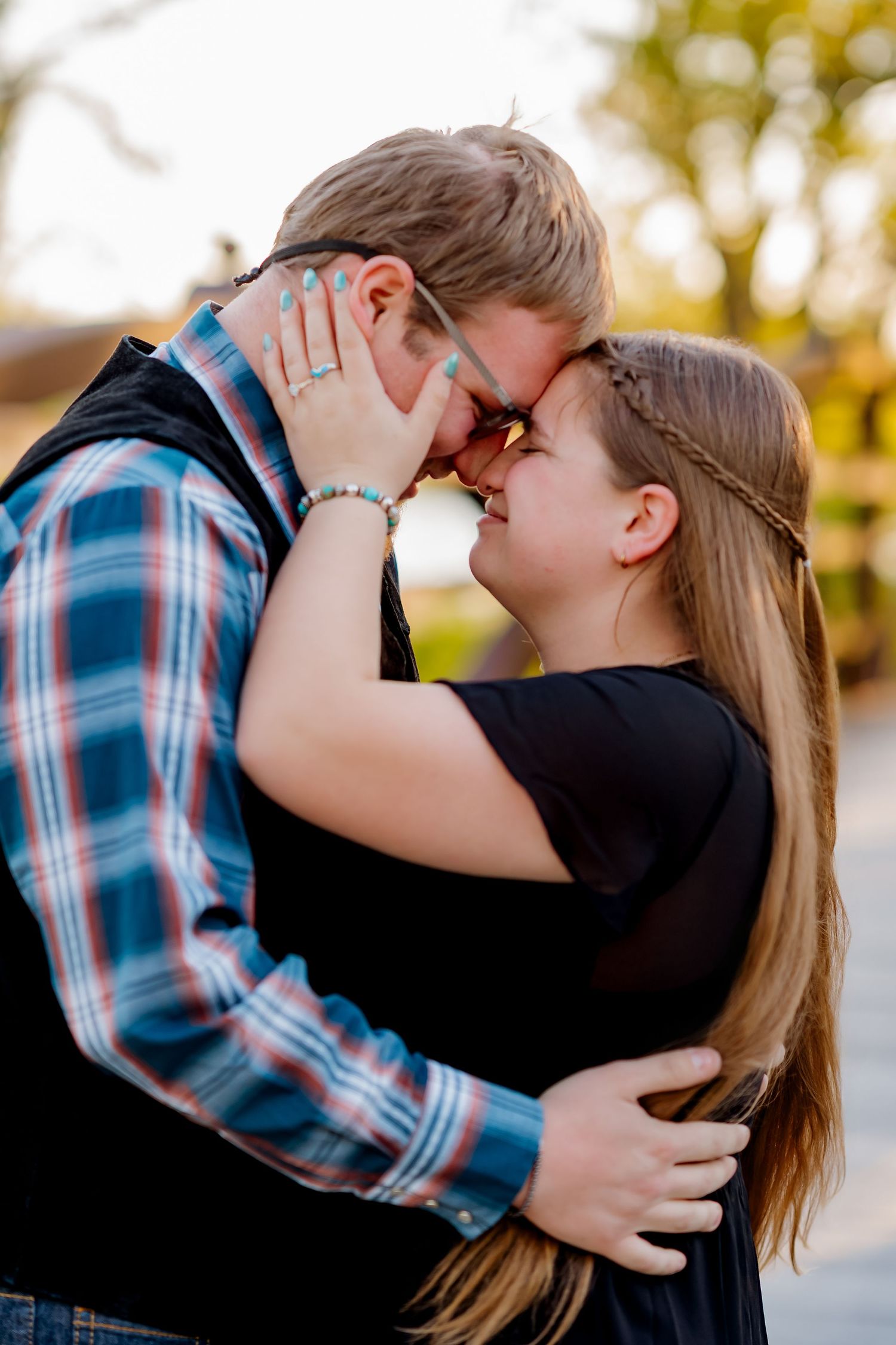 Couple sharing a romantic forehead touch outdoors during golden hour engagement photo session.