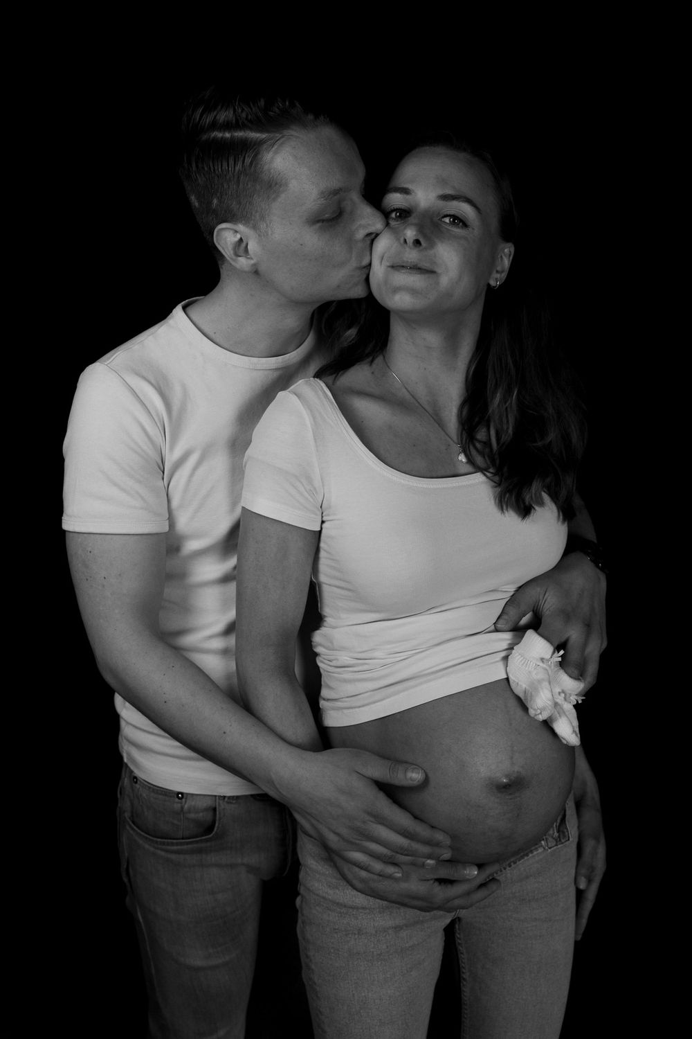 Zwart-wit foto van koppel in studio met flitstechniek- kusje op de wang - zwangerschapsfotografie - Liempde - MaxFotos