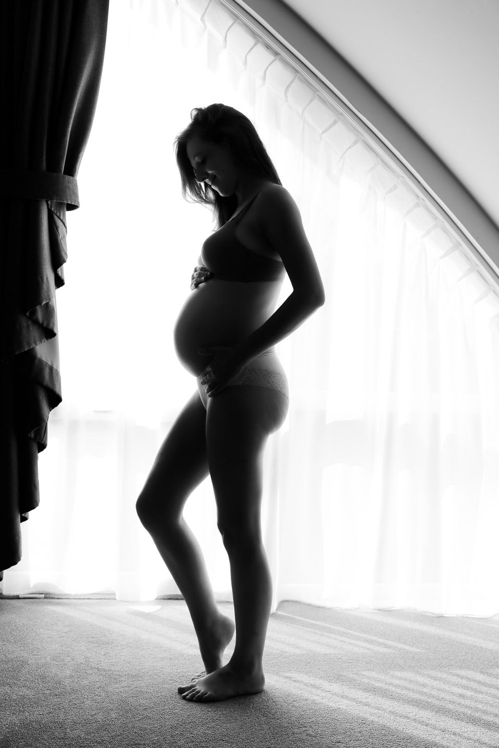 Zwart-wit foto van silhouette van zwangere vrouw met tegenlicht voor het raam - Boutique Hotel Texel - MaxFotos