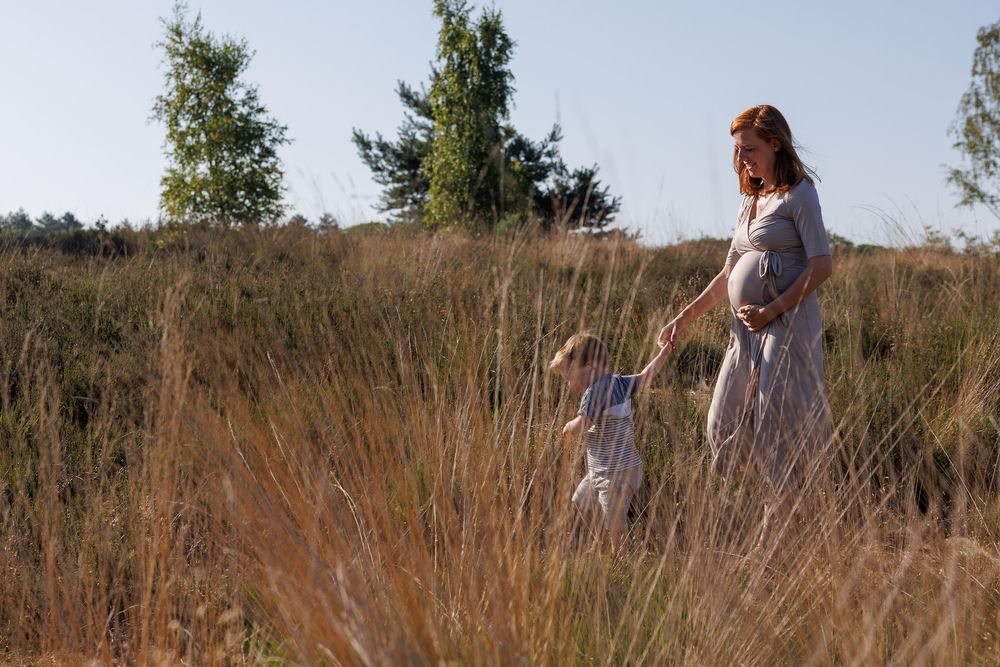 Zwangere vrouw loopt met zoontje over de heide - spontane zwangerschapsshoot - Sonse vennen - MaxFotos