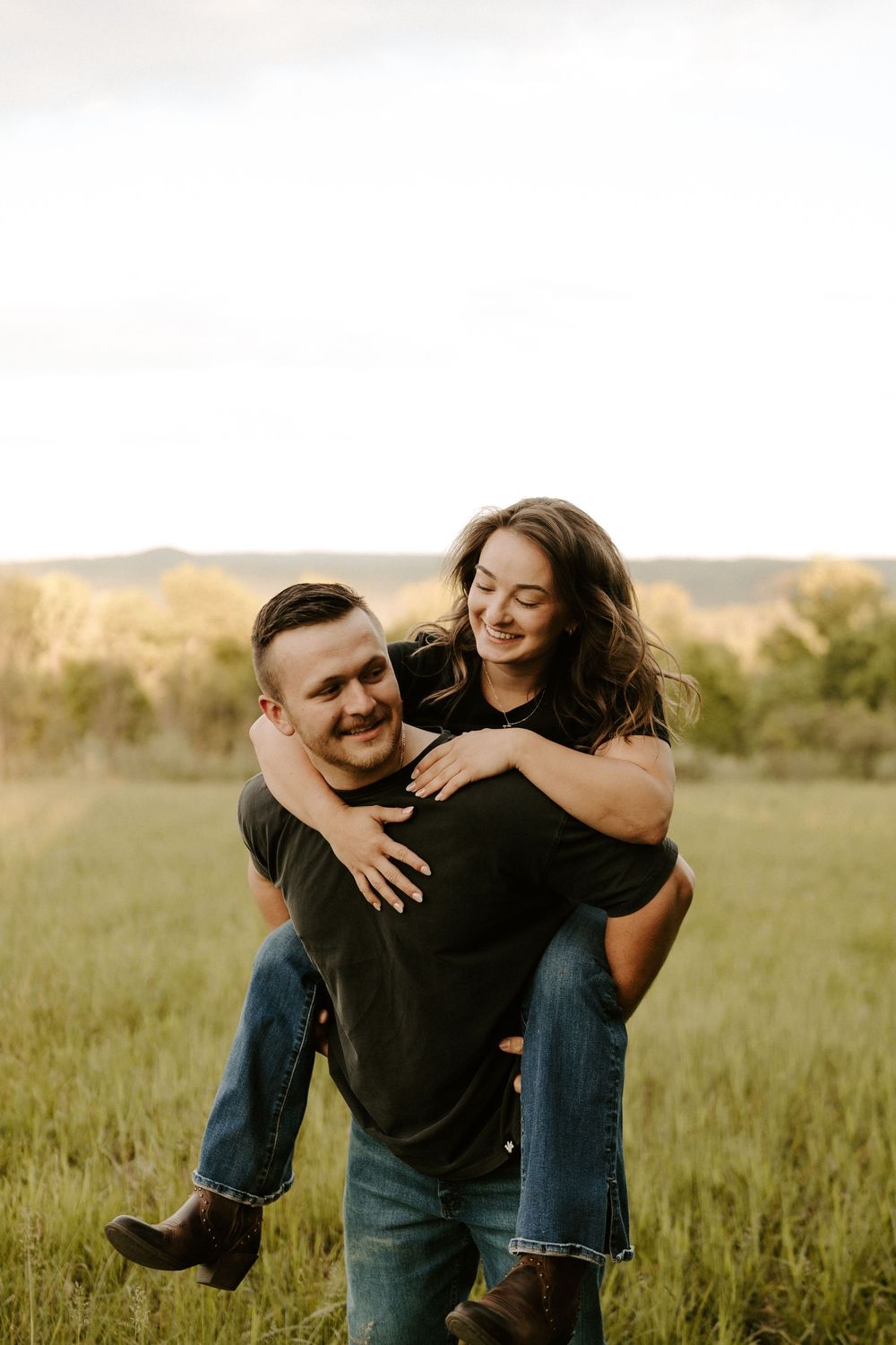A happy couple poses, with the woman being carried on the man's back as they laugh together.