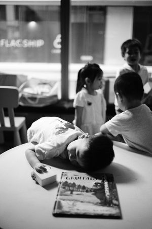 Children gathered around a table with The Gruffalo book in a black and white photo.