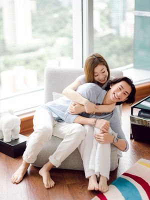 A happy couple sharing a joyful embrace on a cozy armchair in a bright modern living room.