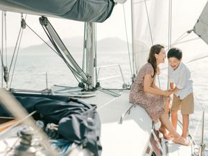 A couple shares a romantic moment together on the deck of a sailing yacht at sea.