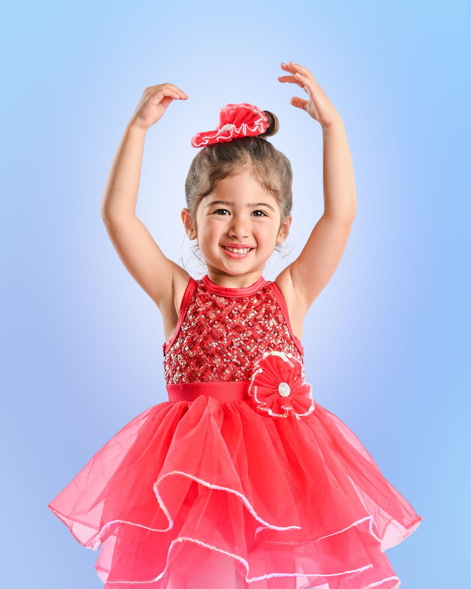 Young girl named Sophie in red sequin dance costume and white tutu poses with hands on hips under sparkly stage lights.