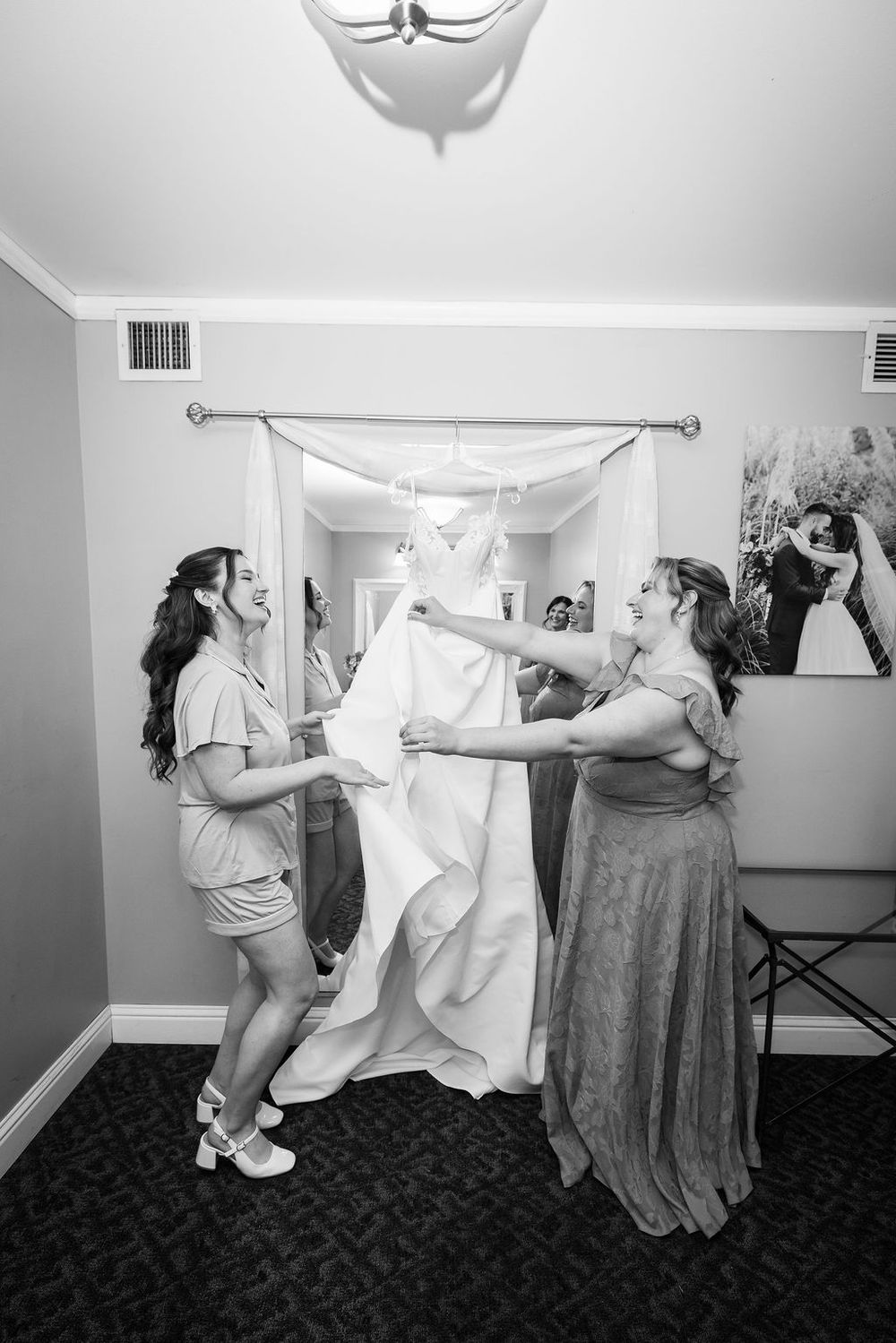Bridesmaids helping with the wedding dress in a black and white getting ready photo.