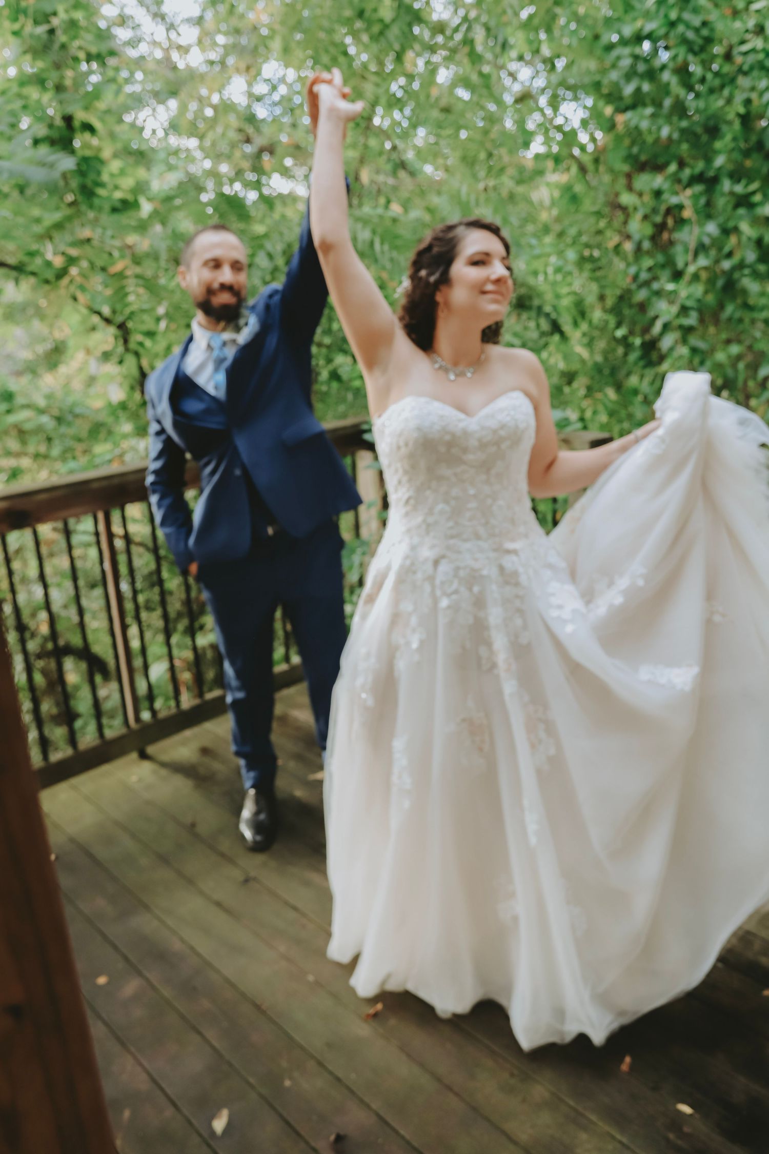 A joyful couple dances on a wooden deck surrounded by greenery.