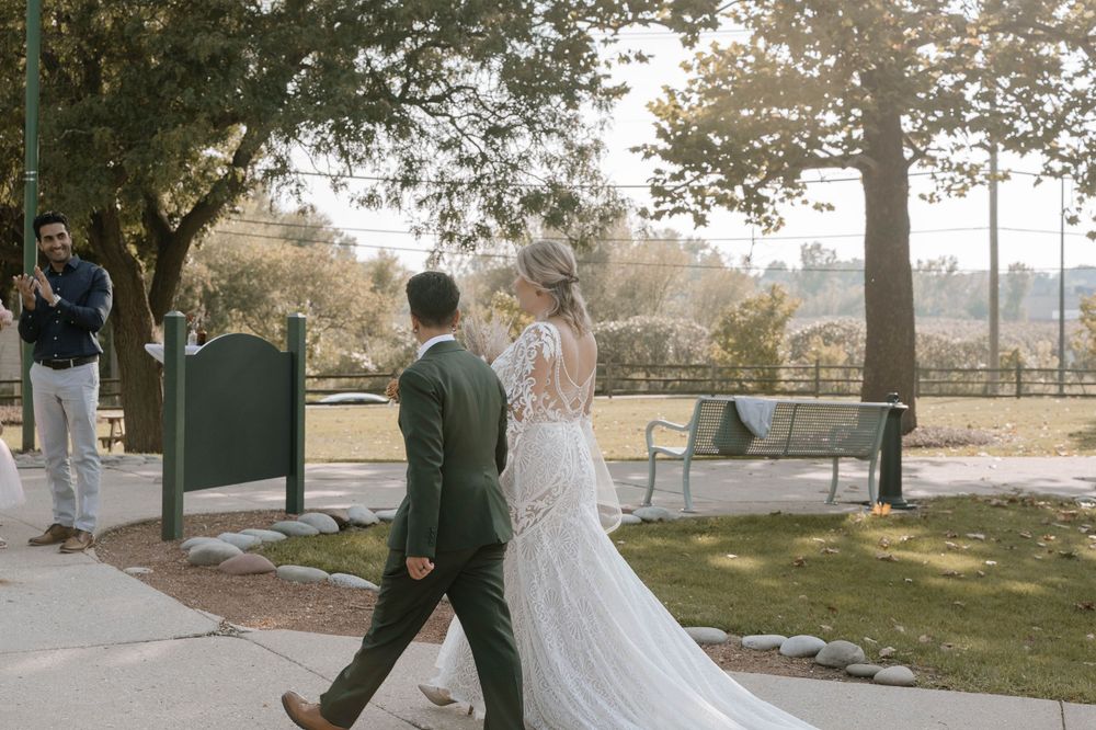 Bride and groom walk together in a park, showcasing elegant wedding attire.