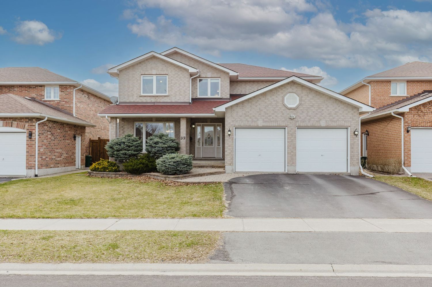 Two-story brick home with double garage, manicured lawn, and paved driveway in a suburban neighborhood.