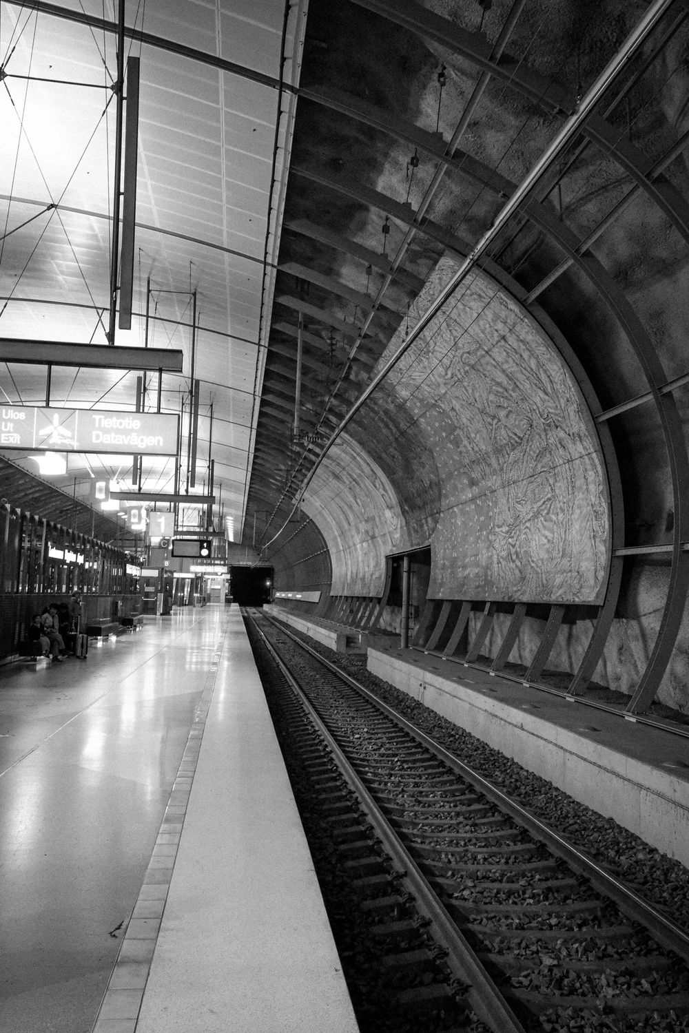Black and white photo of a Helsinki Airport railway station concourse.