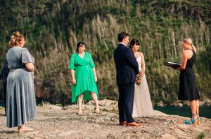 Small wedding party gathered on rocky overlook above a mountain lake.