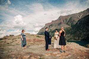 Intimate outdoor elopement ceremony on a rocky mountain overlook with dramatic peaks and lake views.