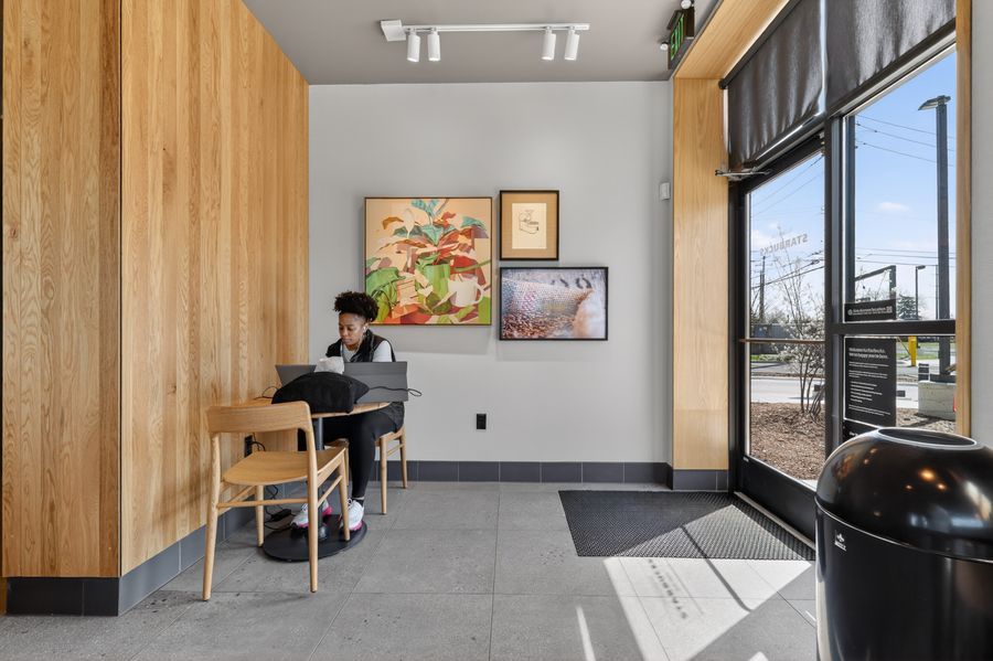 Student working on laptop in modern cafe with wood walls and natural light.
