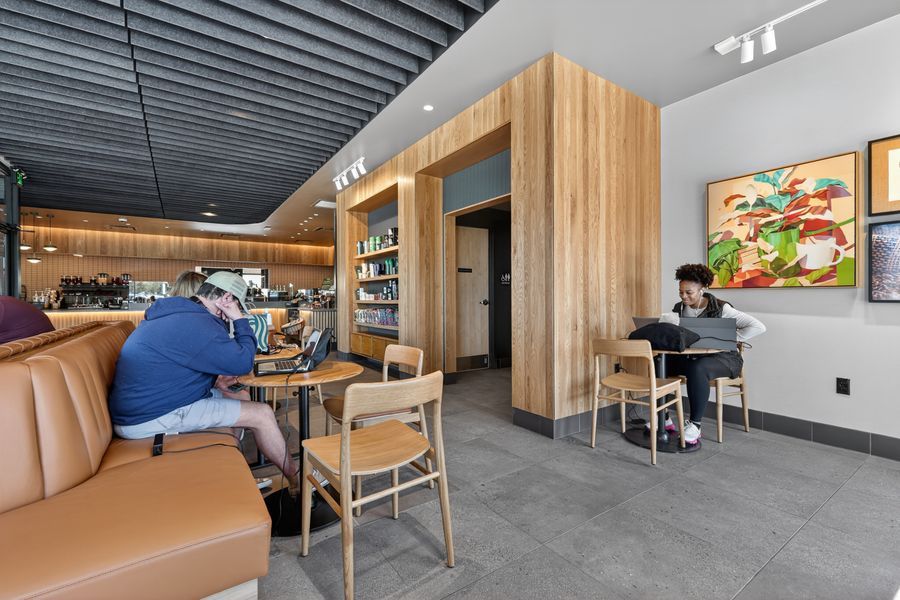 Modern cafe interior with leather booths, wooden accents, and patrons working on laptops in a bright, stylish space.