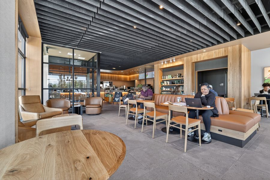 Modern coffee shop interior with wood furniture, leather seating, and open ceiling design.
