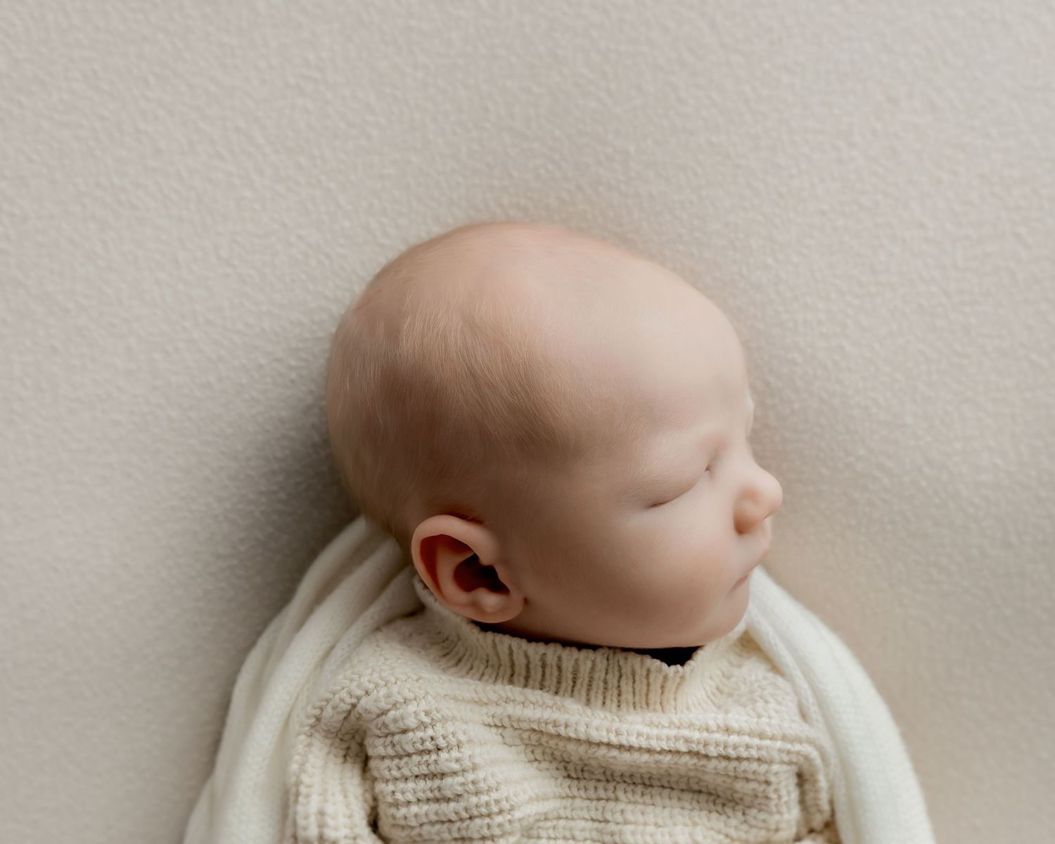Newborn baby wrapped in handmade knit outfit