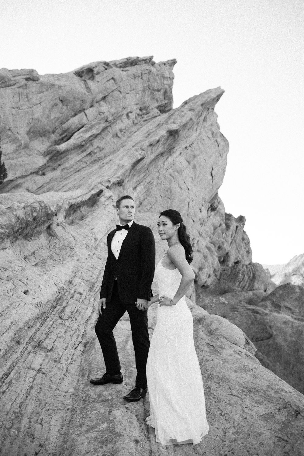 Bride and groom pose on rocky terrain in black and white wedding photo at Vasquez Rocks.