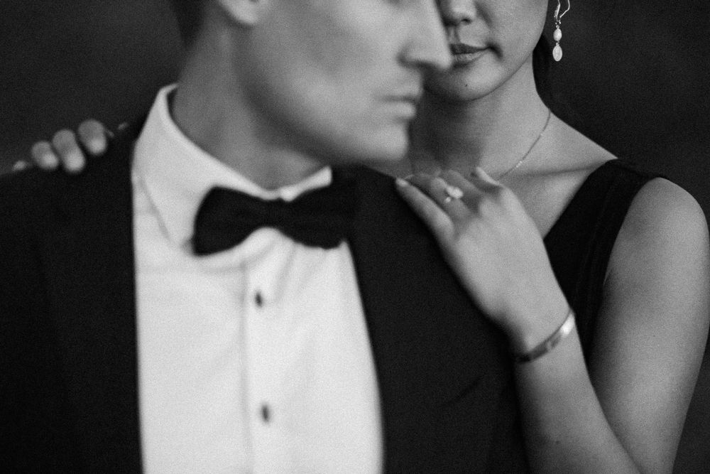 Elegant couple in formal attire posing closely in a black and white portrait photo.