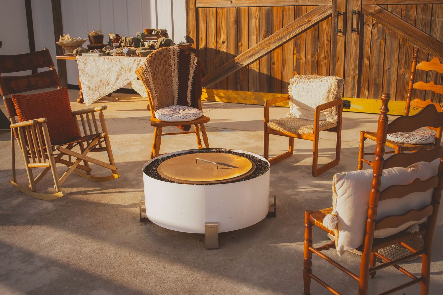 Wooden rocking chairs circle around a metal fire pit outside at The Barn at Palmetto Flats in Fort Pierce, FL