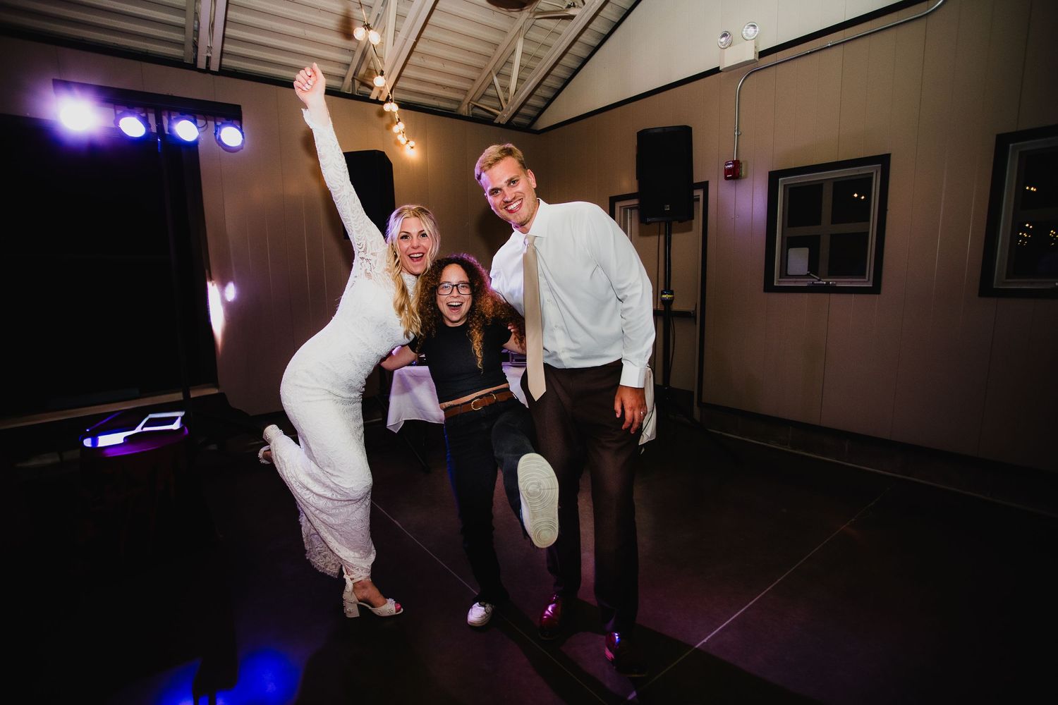 Friends dancing and having fun at a party under purple stage lights.