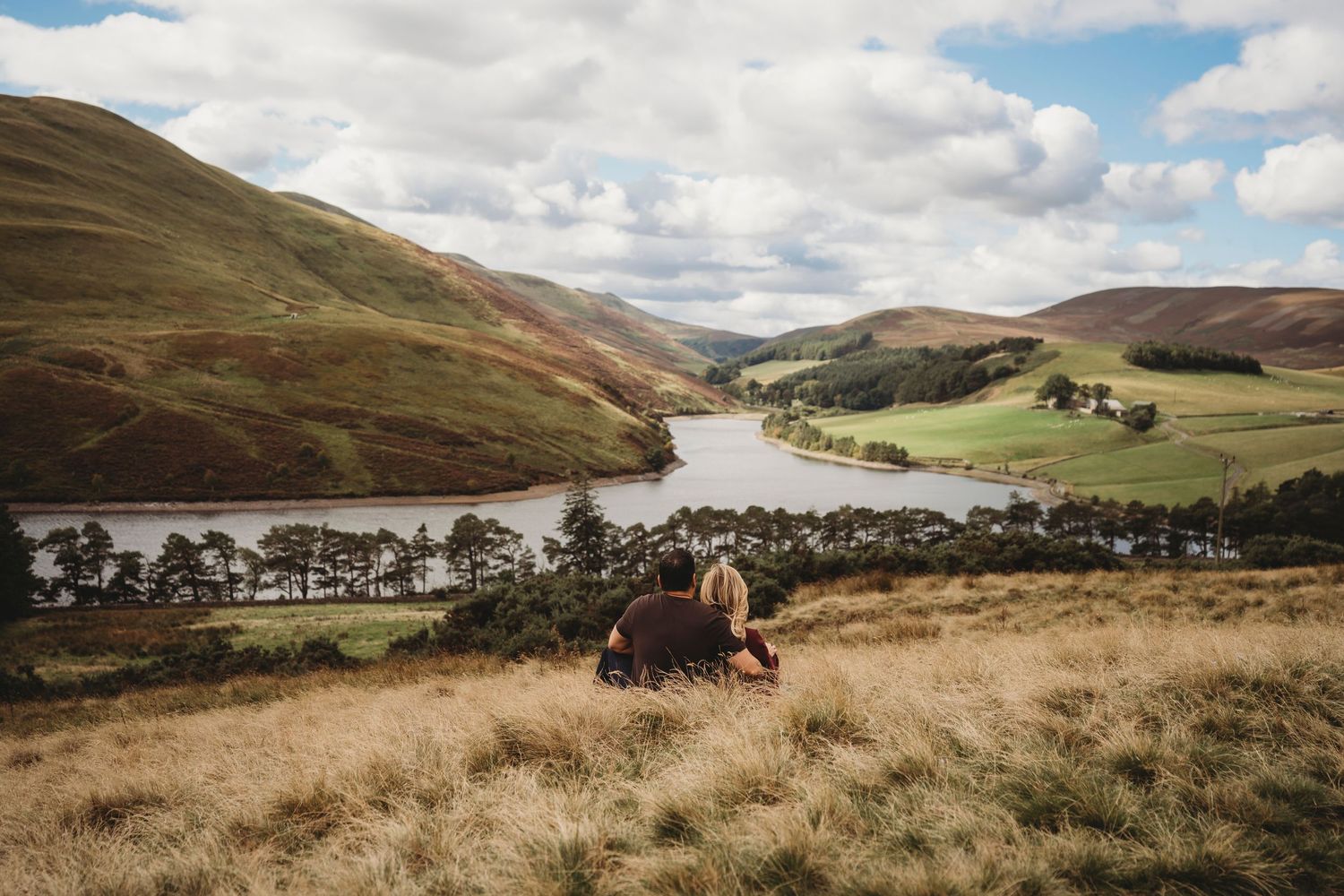 Hikers explore scenic mountain trails with rugged terrain and rolling hills in the distance on a cloudy day.