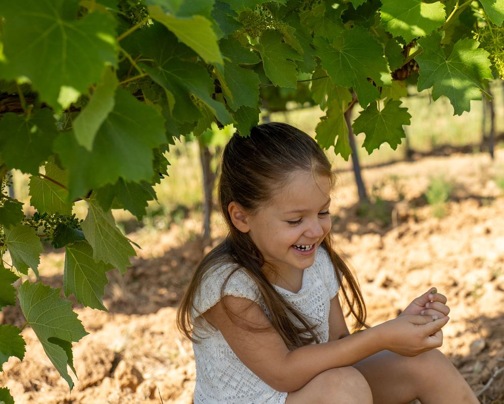 Enfant assise sous les vignes pendant une séance photo famille naturelle en Provence