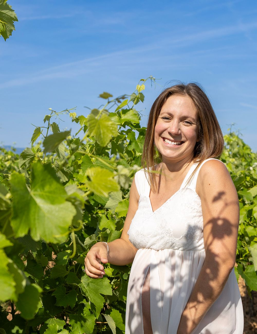 Portrait d’une future maman souriante dans les vignes pendant un shooting grossesse dans le Var