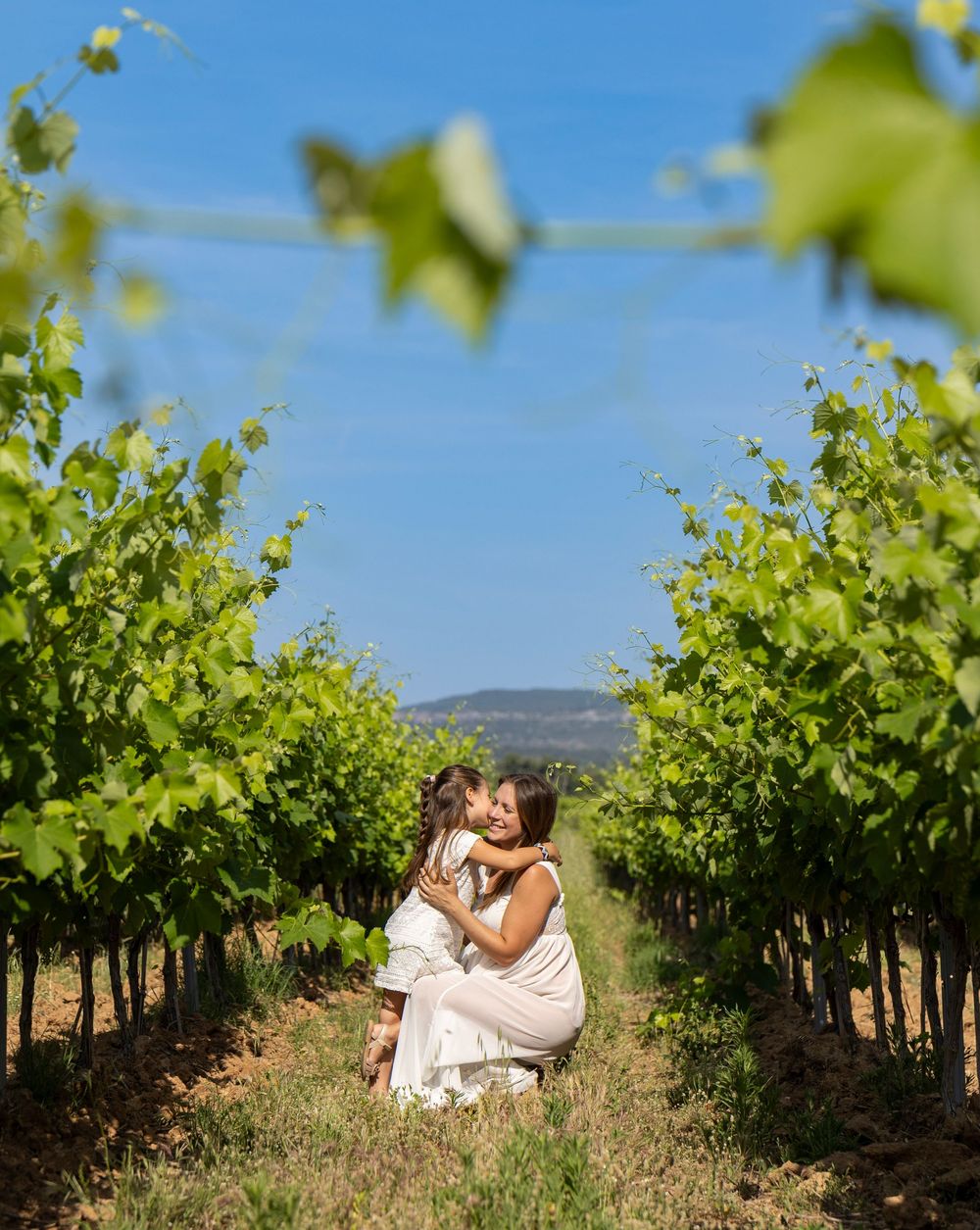 Future maman assise au milieu des vignes pendant un shooting maternité naturel dans le Var