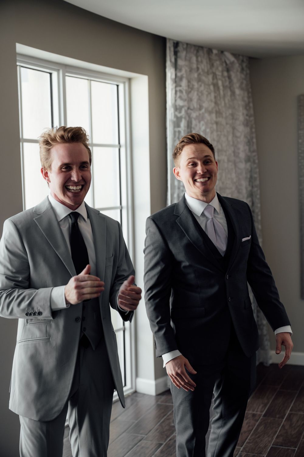 A sequence of four candid moments showing joyful laughter and genuine reactions in matching grey suits.