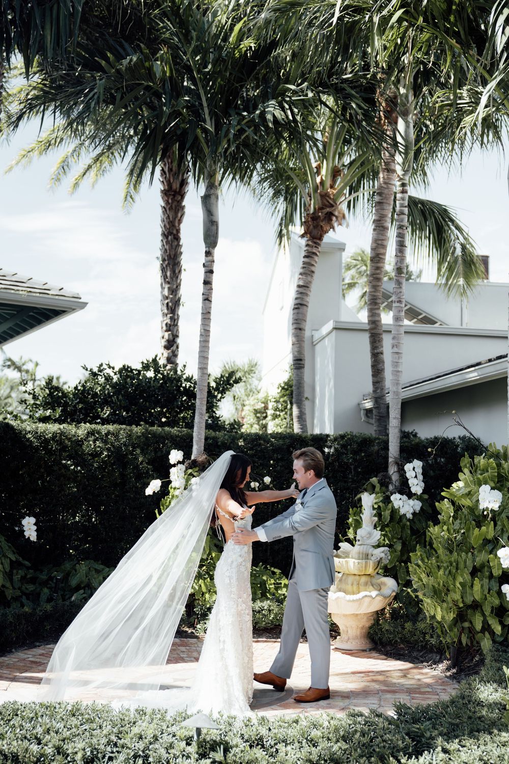 Joyful couple sharing romantic dance moves in a tropical garden setting with palm trees and white architectural details.