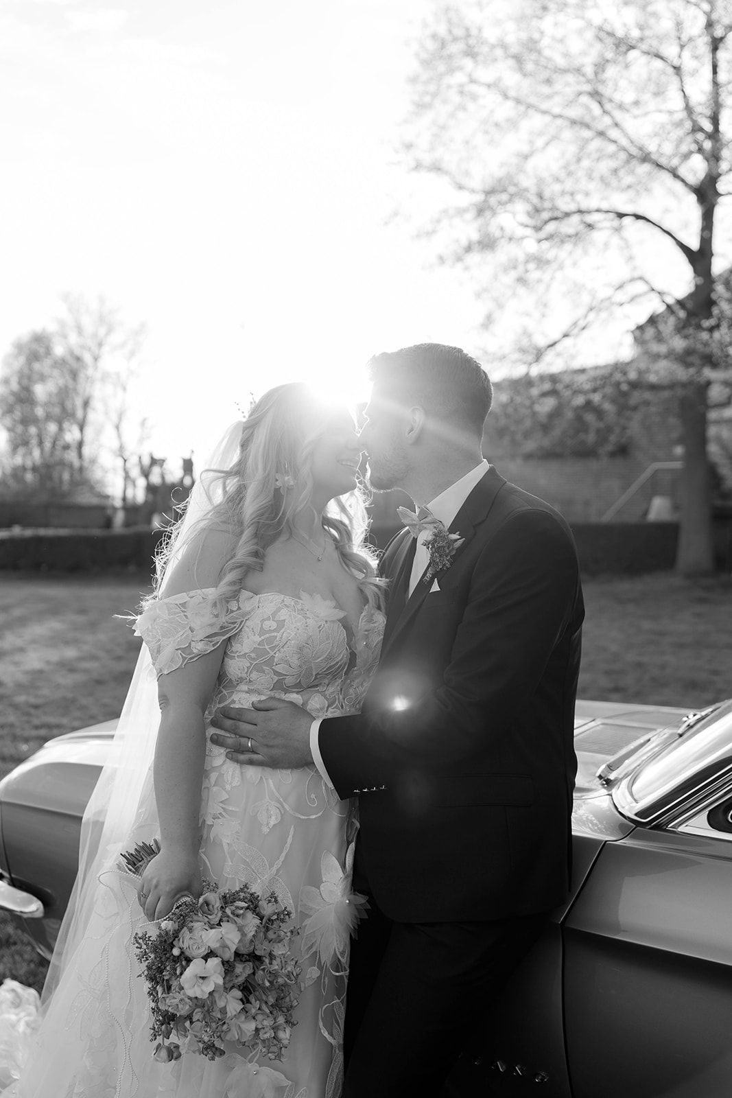 Romantic black and white wedding photos showing tender moments between newlyweds next to a classic car.