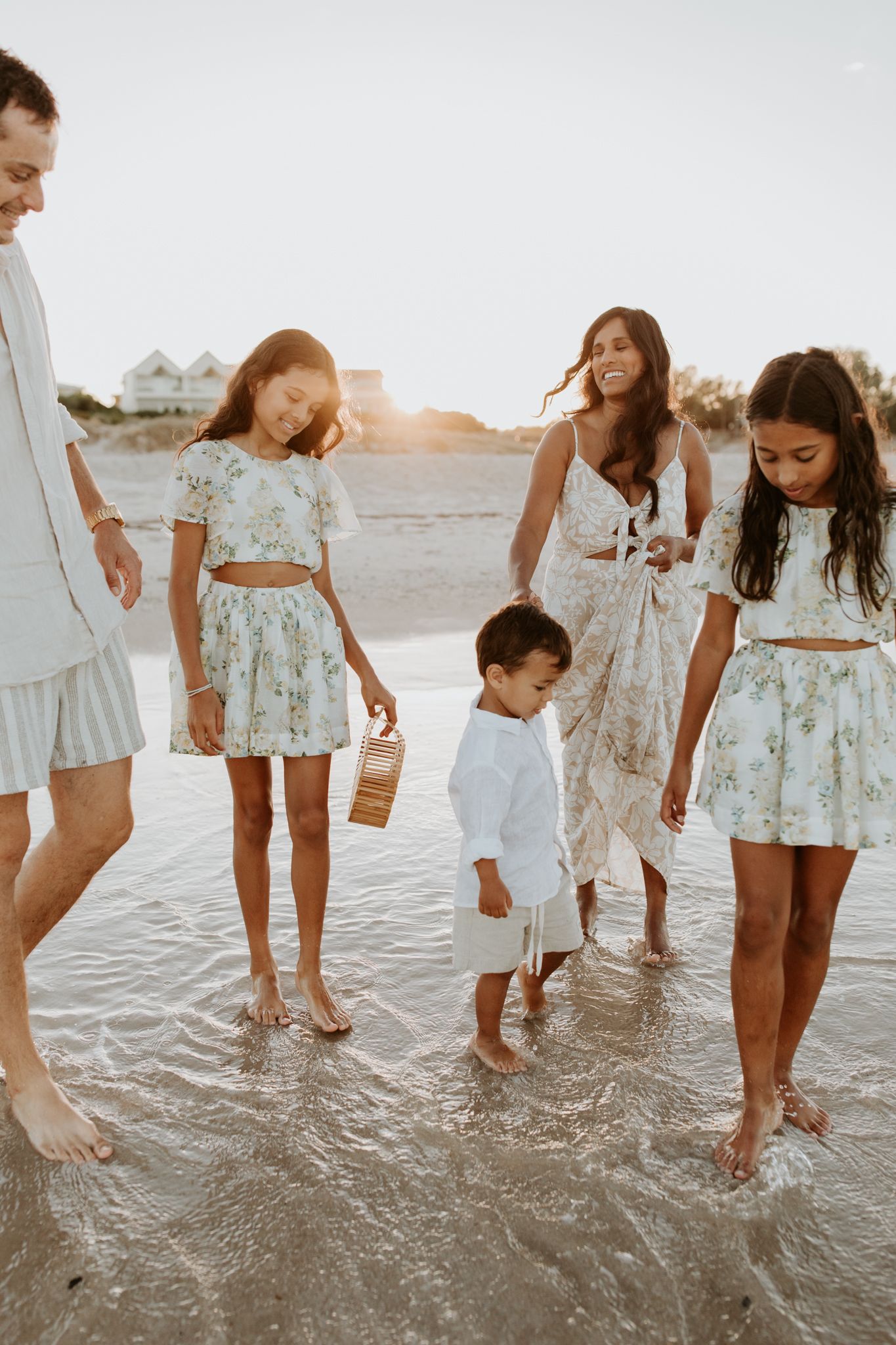 Candid family of five laughing and playing in the ocean at sunrise at West Beach, Adelaide, surrounded by a golden glow.