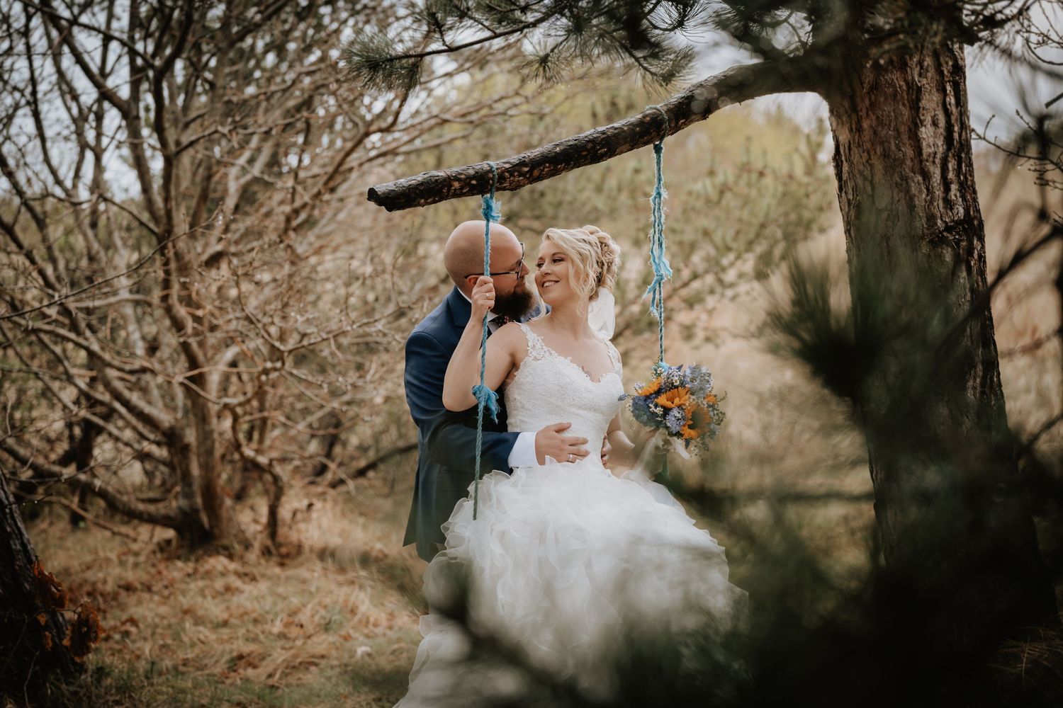 A couple walks among autumn trees with sunlight filtering through branches during an outdoor wedding ceremony.