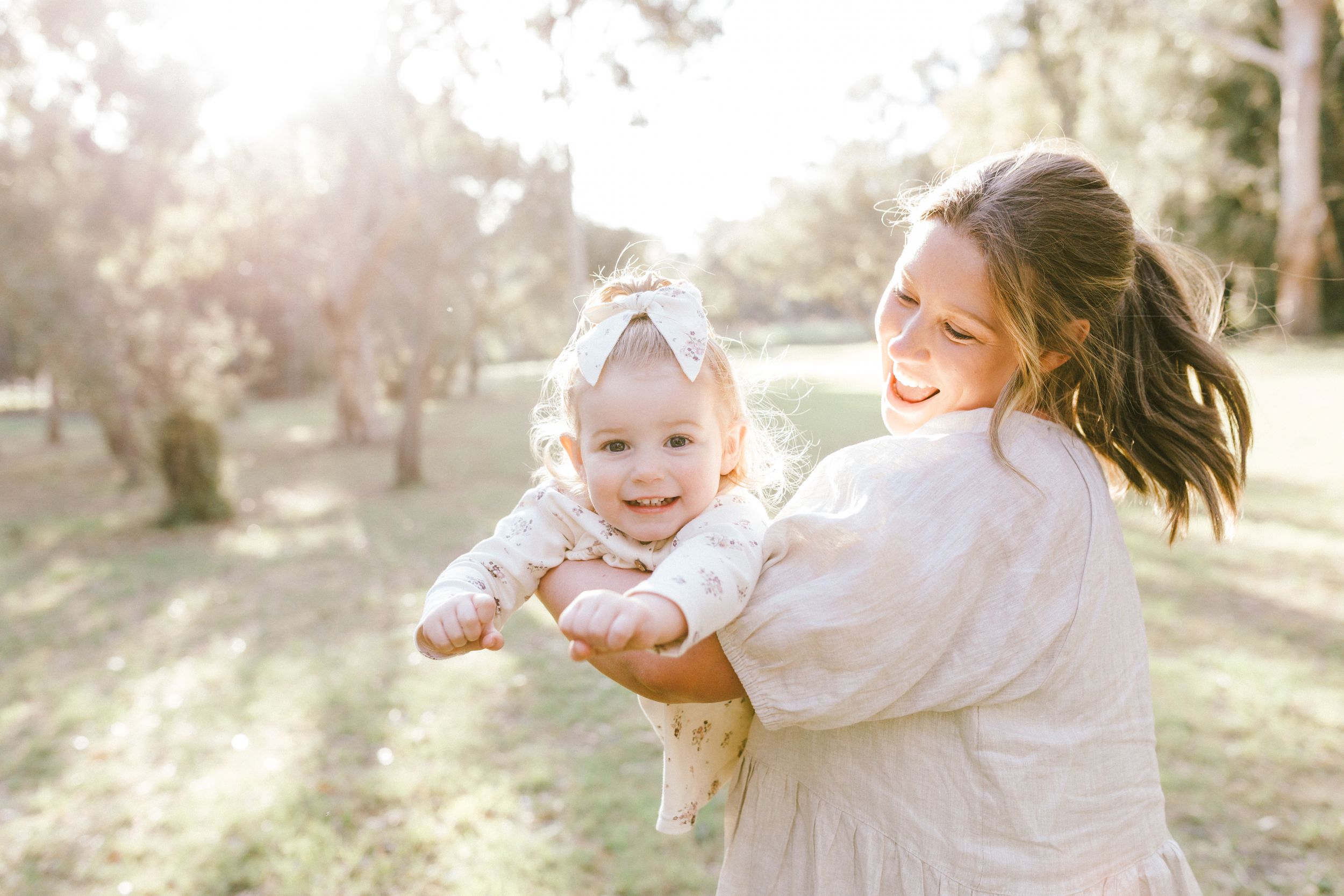 Family playing and spinning together in a sun-drenched outdoor setting during golden hour.