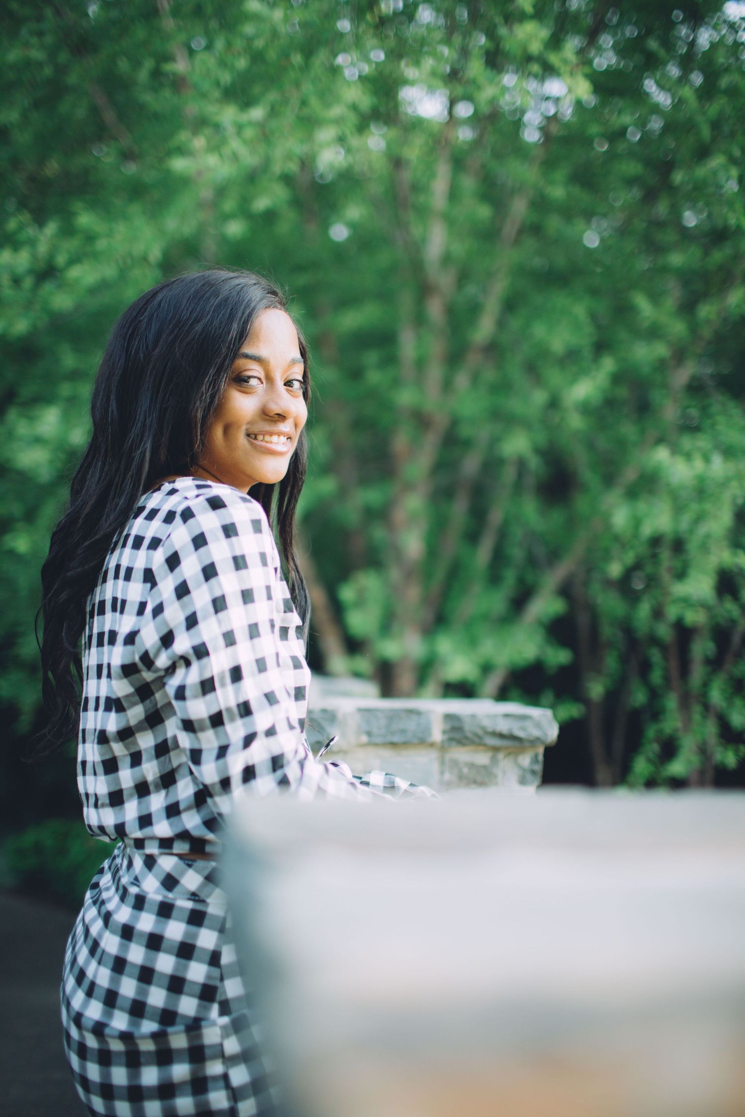 Woman in black and white checkered shirt sitting outdoors in natural setting, shown in series of similar poses.
