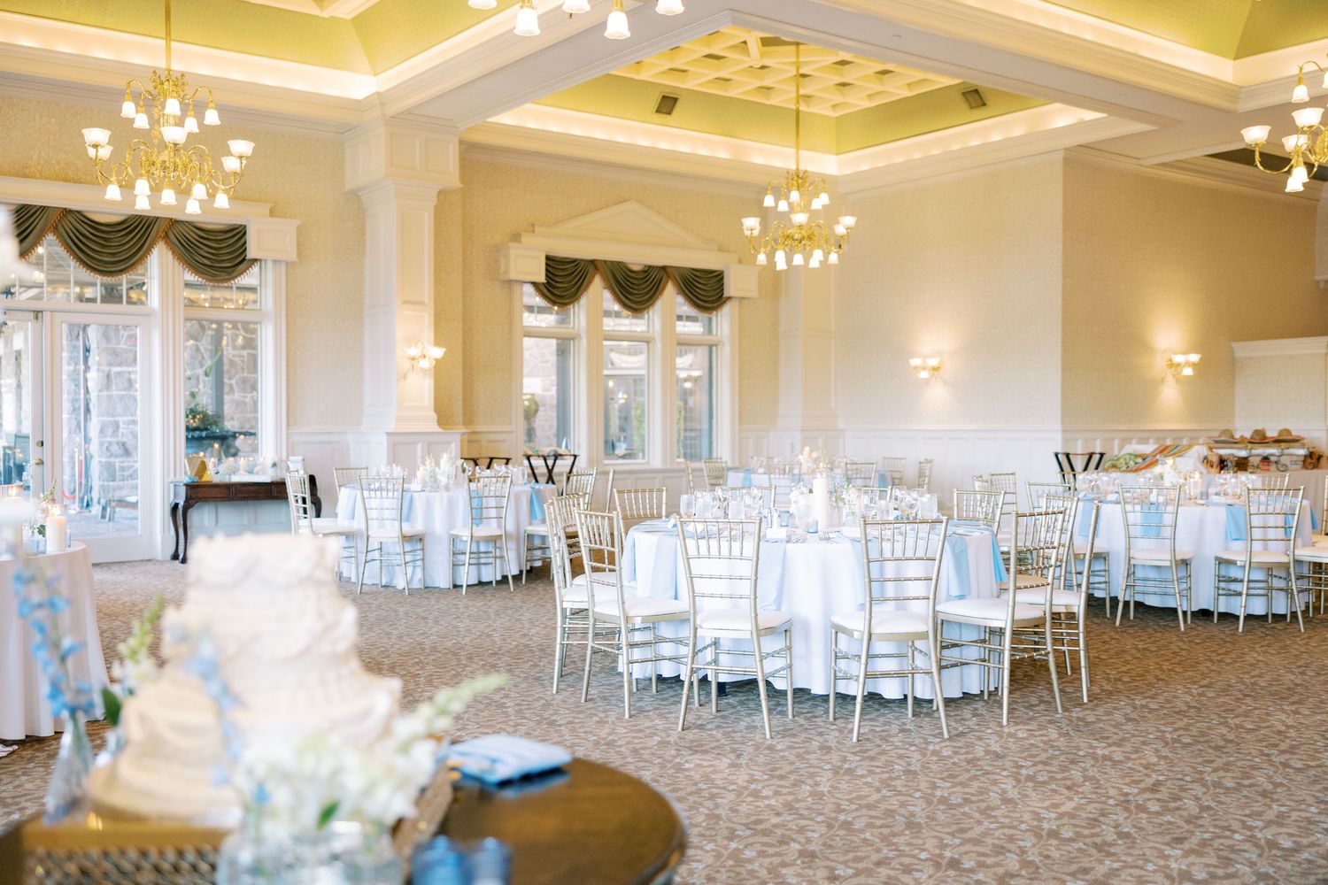 Elegant ballroom with crystal chandeliers and white Chiavari chairs set up for a wedding reception.