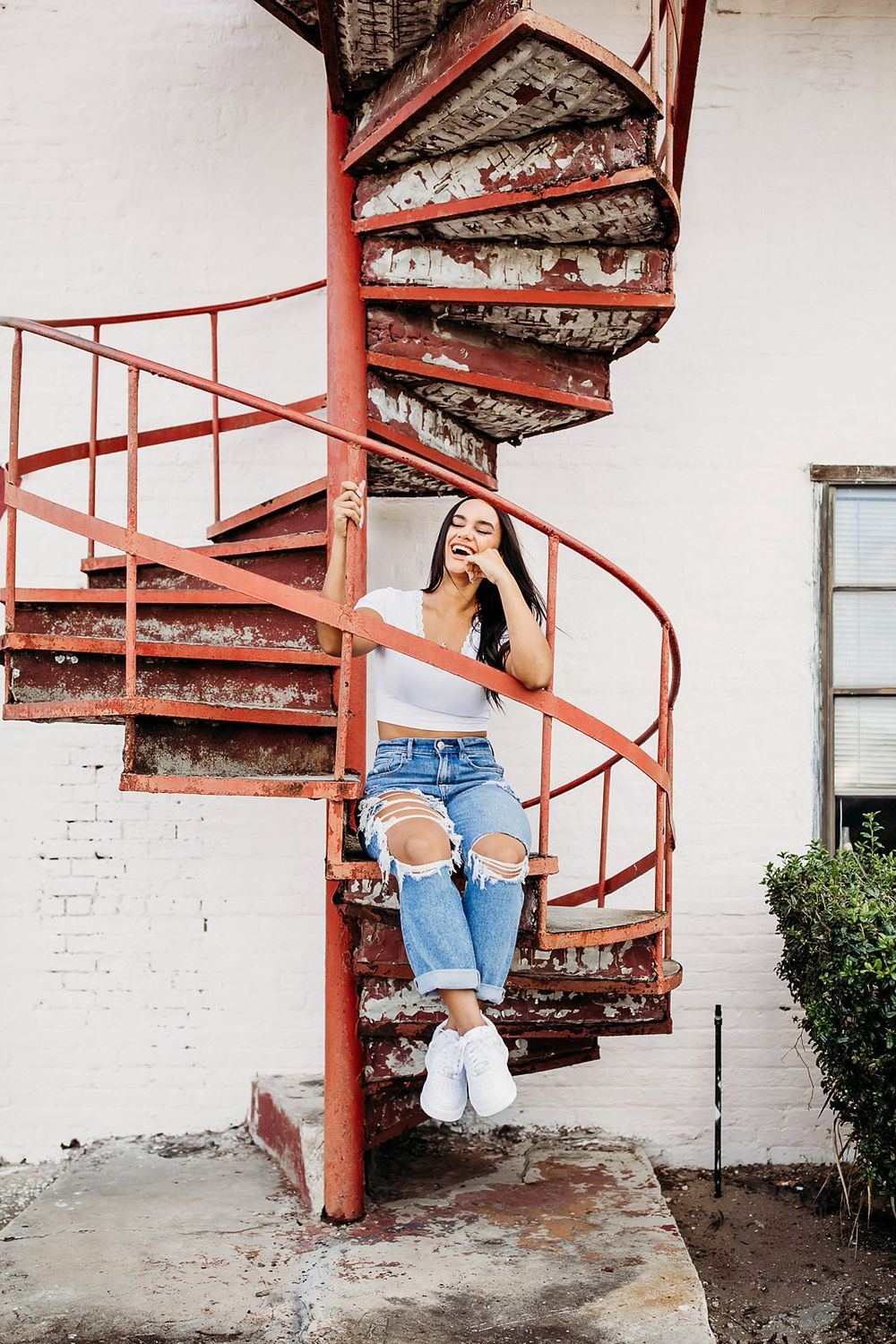 A sequence of artistic shots showing movement down a red spiral staircase against a white brick wall background.