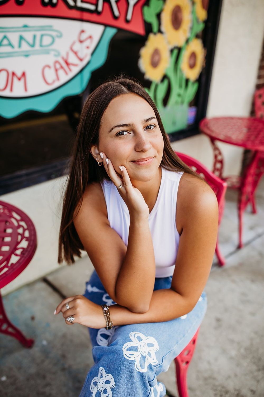 A series of portraits showing someone posing outdoors in a white tank top and light denim against a colorful wall background.