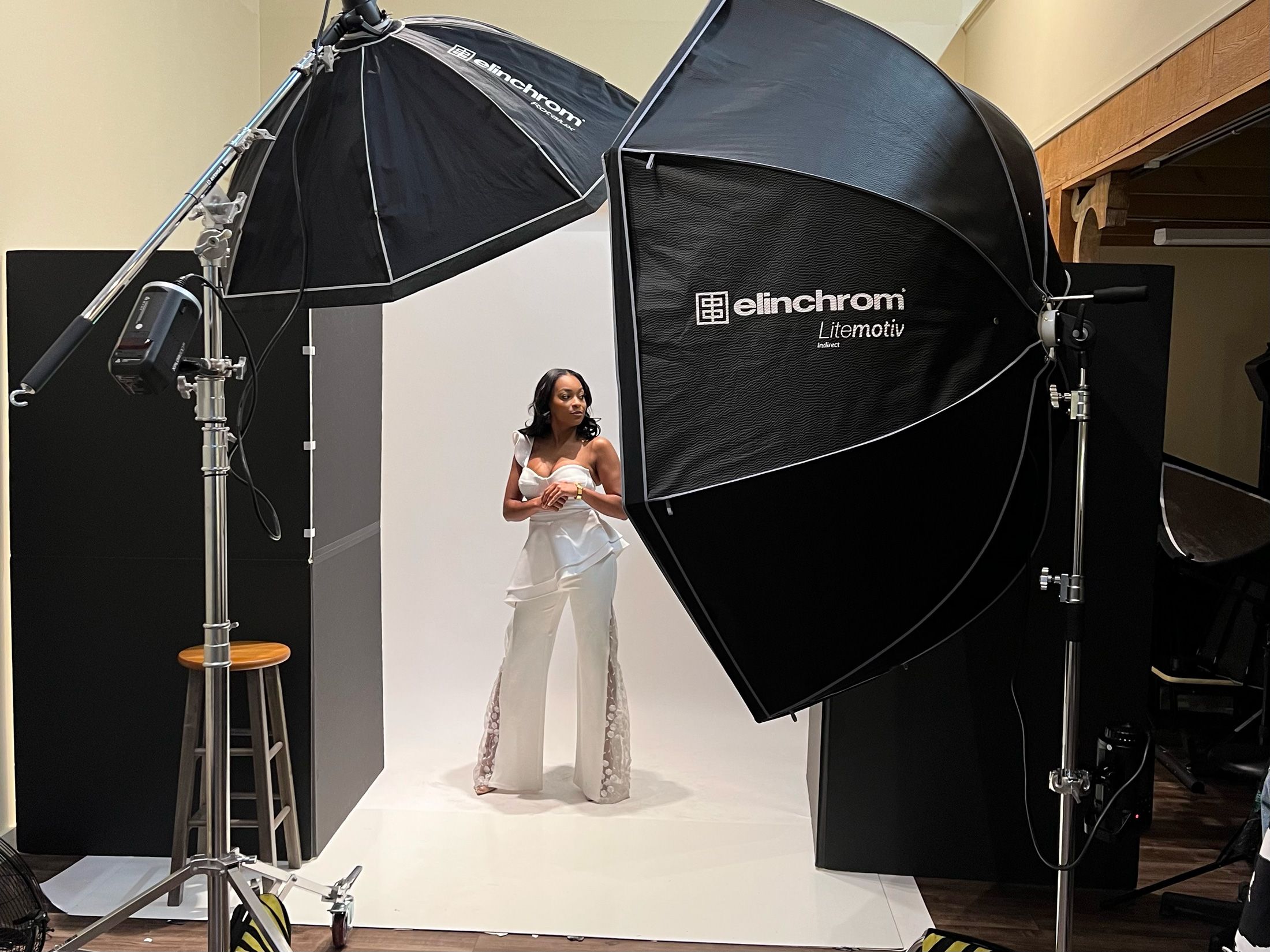 Behind-the-scenes photo of a professional photo studio setup with lighting equipment and white backdrop.