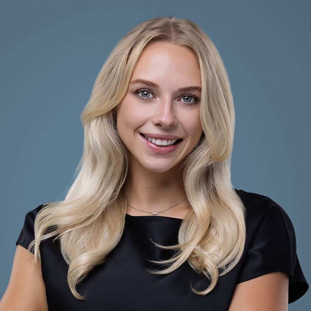 Professional headshot series of a woman with blonde wavy hair and a black top against a blue-grey background.