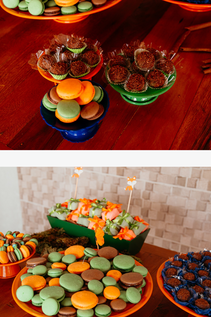 Colorful macarons arranged on plates with orange, green, and blue cookies displayed on a dark wooden surface.