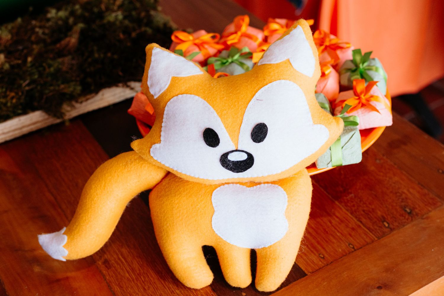A series of plush fox toys with white and orange coloring arranged in a row on a wooden surface.