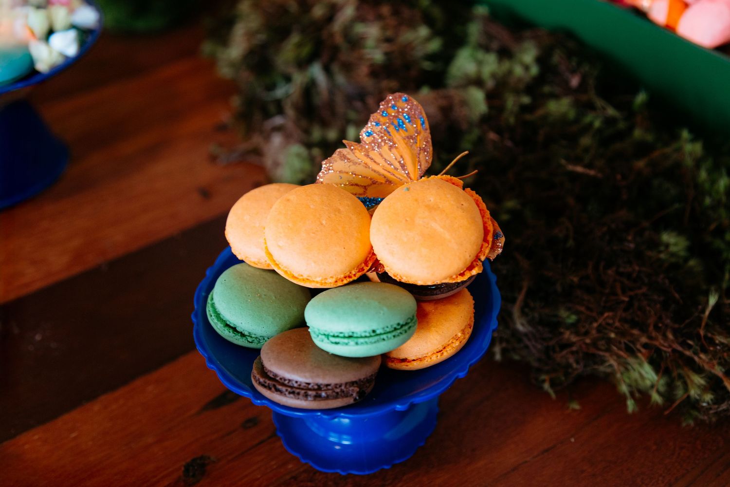 Colorful French macarons arranged in various blue and orange bowls against a dark background.