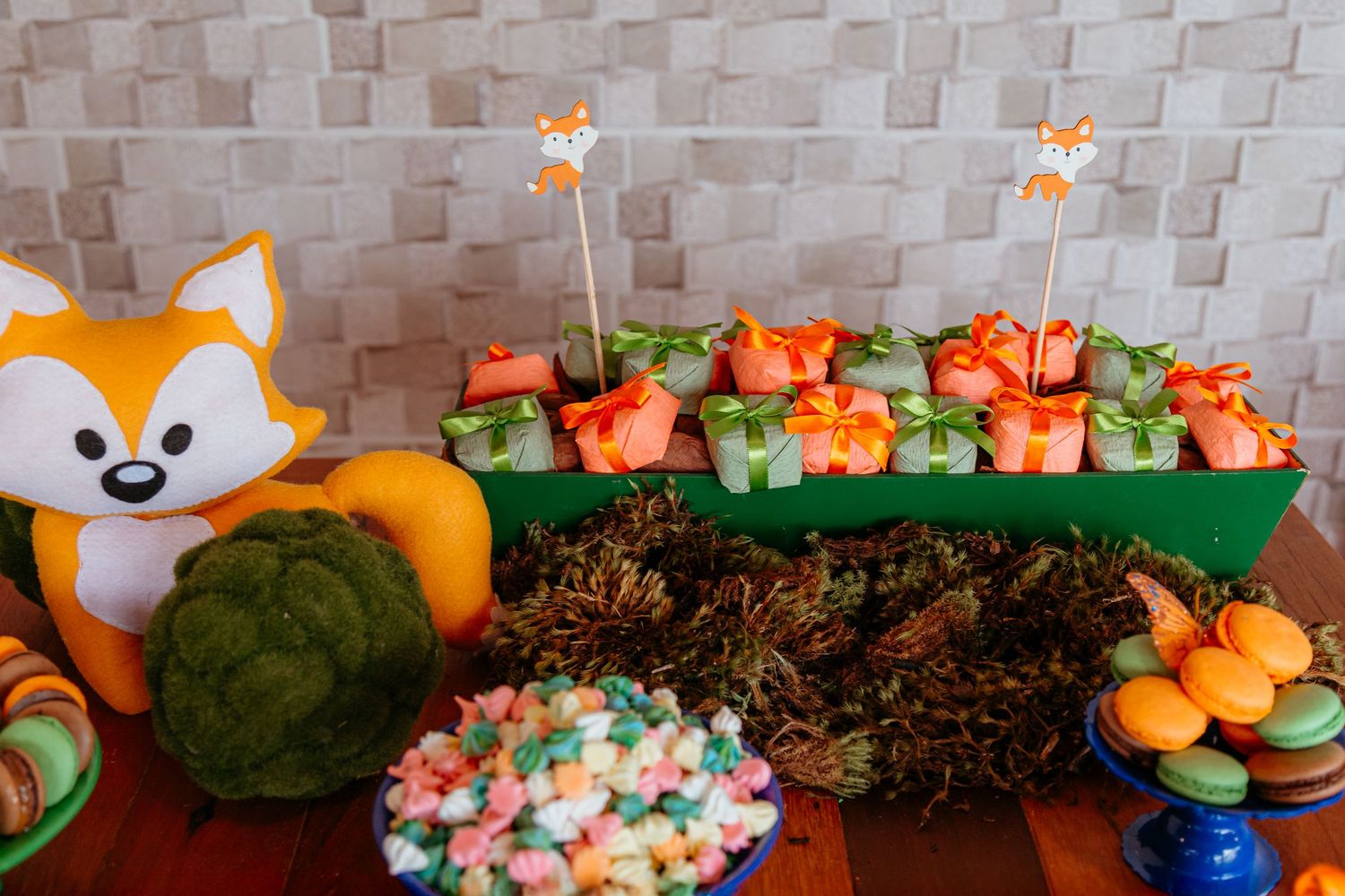 Orange and white woodland animal themed party decorations with treats and snacks arranged on a dessert table.
