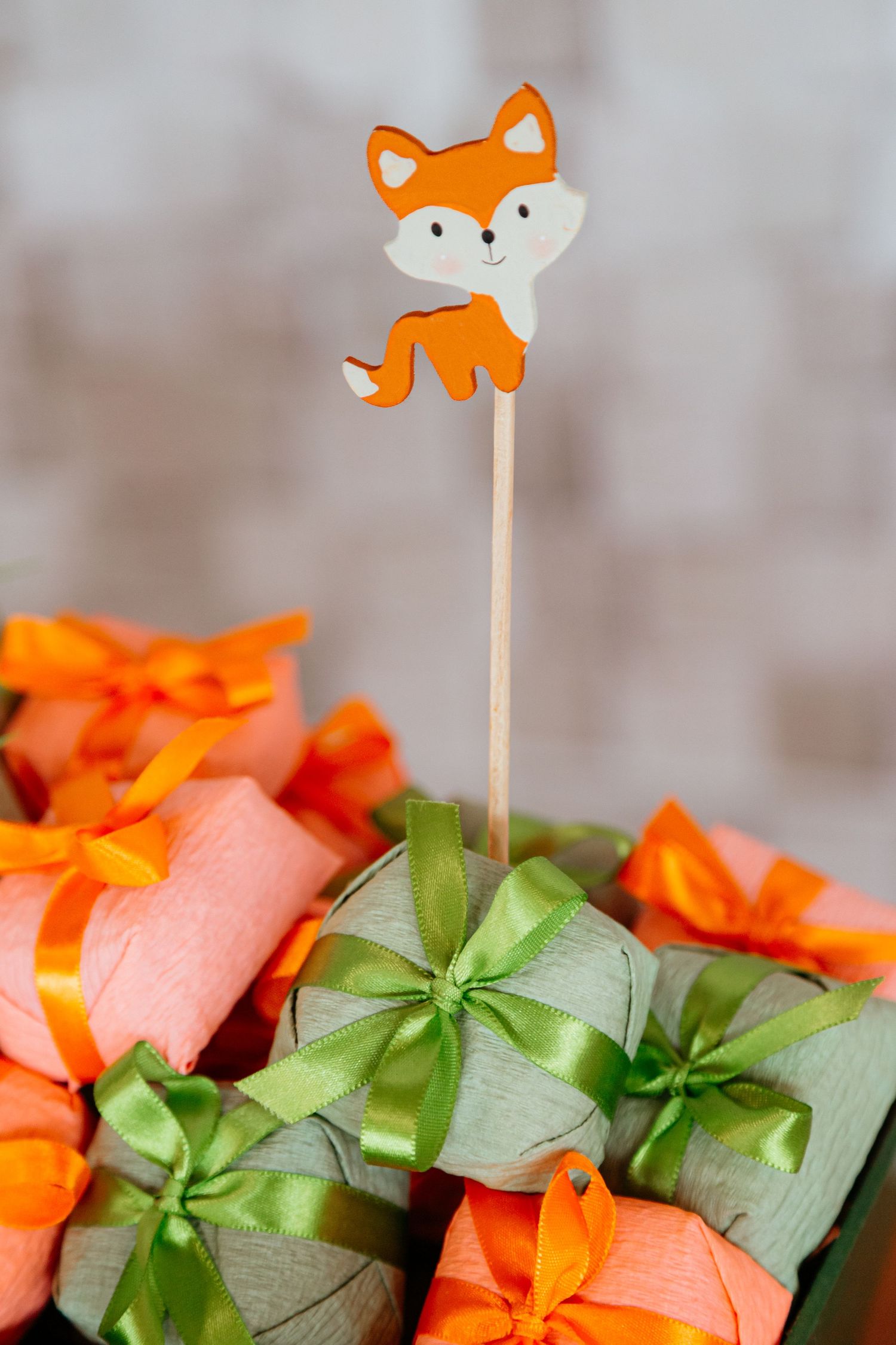 Decorative orange and green tissue paper craft flowers with cute animal-themed lollipop sticks as party decoration.