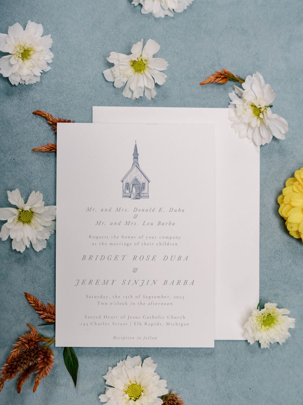 Elegant wedding invitation with floral accents on blue background.