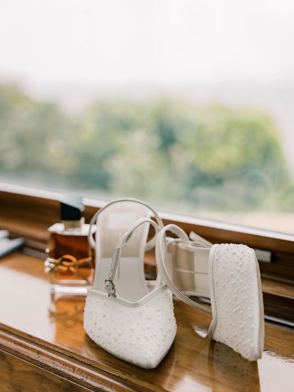 White wedding heels arranged artistically on a wooden windowsill.