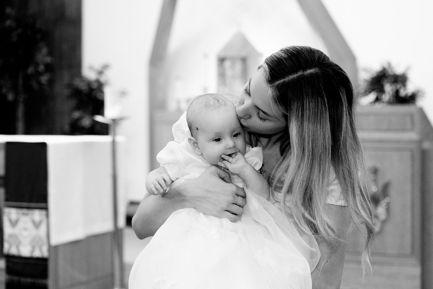 A tender moment as a parent comforts and holds their baby during a religious ceremony.